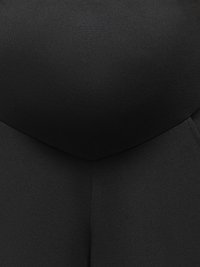 Close-up of a person wearing black leggings and a black fitted top, focusing on the waist and hip area.