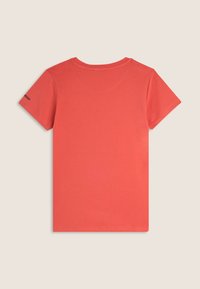 Camiseta de manga corta en algodón color coral. Presenta un cuello redondo y un pequeño logo en la manga izquierda. Textura suave, diseño simple.