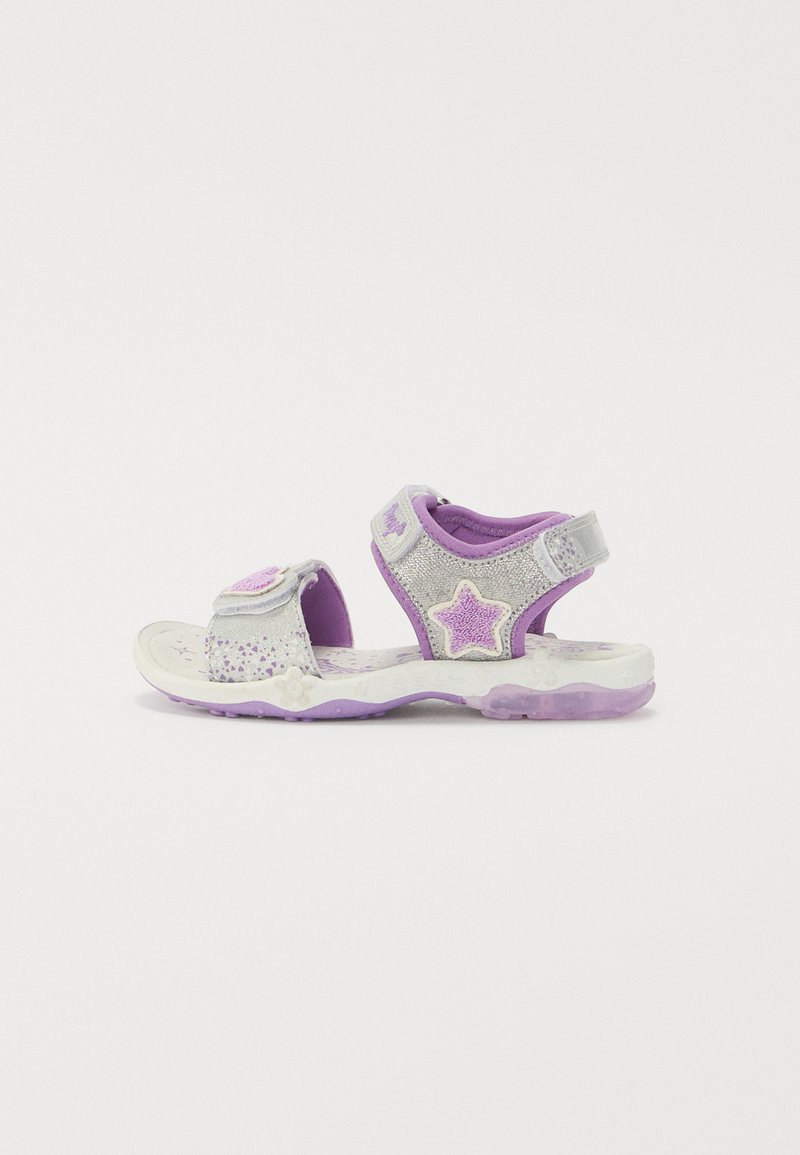 Lila und silberne Kindersandalen mit Sternelementen, Klettverschlüssen, glitzerndem Material und einer strukturierten, gemusterten Sohle.