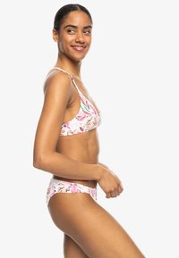 Baddräktsset med blommönster i rosa och grönt, med tunna remmar och en låg midja bikiniunderdel, tillverkat av stretchy tyg.