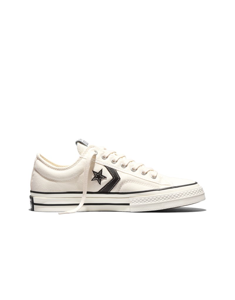 Witte lage sneakers van canvas met een zwart sterren- en chevronlogo, witte veters en een rubberen zool met zwarte strepen.