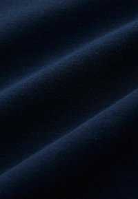 Tengerészkék anyag sima tapintással, finom, egyenletesen elosztott varratokkal készült kötött mintát mutat, és lágy eséssel rendelkezik.