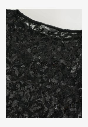 Haut en dentelle noire avec des détails en sequins, présentant une finition douce et texturée ainsi qu'une encolure large. Étiquette de la marque "NEXT" visible à l'intérieur.