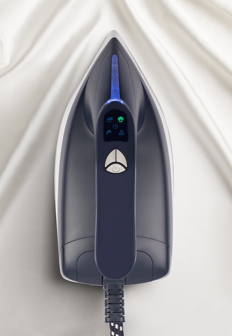 Fer à repasser à vapeur sur un tissu blanc avec un affichage numérique montrant le mode éco, des icônes d'eau et de connectivité, ainsi que des boutons de contrôle sur la poignée.