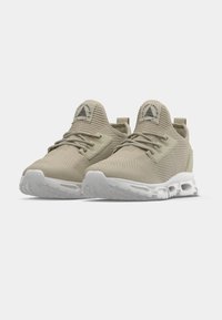 Világos bézs atlétikai cipő texturált hálós felsőrésszel, elöl fűzővel, lekerekített orral és fehér párnázott talppal. Logó a sarokpánton.