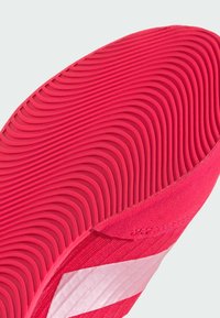 Sole di scarpa di un brillante colore rosa, caratterizzata da scanalature ondulate testurizzate. La parte superiore presenta dettagli rosa chiaro con una finitura liscia e un design a strisce in contrasto.