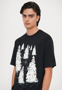 Musthave mustaga, millel on graafiline trükk lumega kaetud puudest, mida kaunistavad punased aktsendid. Lühikesed varrukad ja ümar kaelus. Pehme kangast tekstuur.