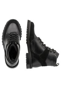 Czarne skórzane i zamszowe botki za kostkę z okrągłym noskiem, z fasonem na sznurowanie, teksturowaną podeszwą i gumową podeszwą zewnętrzną. Posiada akcenty panelowe i pętlę do wciągania.