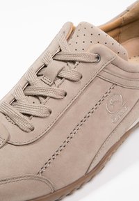 Baskets beige clair en daim, avec un bout perforé, des lacets ronds, des coutures latérales et une semelle en caoutchouc texturée.