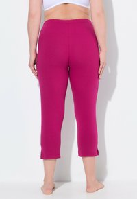 Fitted capri leggings in bright fuchsia, made of soft cotton-blend fabric. Features an elastic waistband and side slits at the hem.