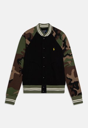 Veste noire boutonnée avec manches camouflage, col et poignets rayés, deux poches avant, et petit logo jaune de cheval sur la poitrine.