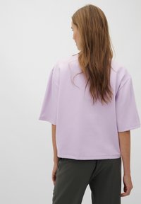 Levandulové oversized tričko s krátkým rukávem, vyrobené z měkké látky. Má uvolněný střih a plochý lem, s minimálními švy.