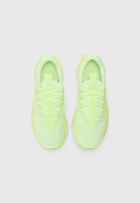 Baskets de sport jaune fluo avec une tige en maille légère, des lacets plats et un col rembourré. Présentent un design texturé et des accents de logo.
