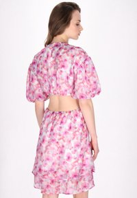 Twee-delig outfit van lichtgewicht, bloemenstof met roze en paarse tinten. Korte pofmouwen en een open rugontwerp met een elastische tailleband.