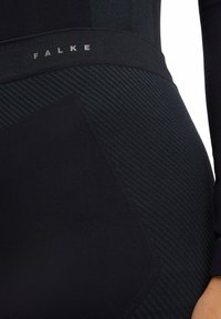 Black leggings by Falke featuring a textured waistband and diagonally striped pattern. Material appears smooth with a slight sheen.