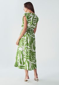 Zelena i bijela maxi haljina s uzorkom napravljena od laganog materijala, s opuštenim krojem, nabranim detaljima u struku i kratkim rukavima.