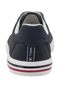 Baskets en toile bleu marine avec une finition texturée, une doublure intérieure blanche et une semelle blanche ornée d'accents rayés rouges et noirs. Logo à l'arrière.