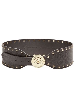 Zwarte gestructureerde leren riem met gouden studs en een ronde gouden gesp gegraveerd met "GUESS 1981 LOS ANGELES."