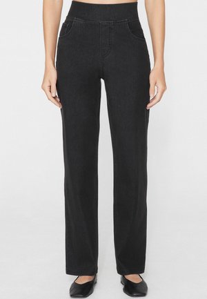 Pantaloni neri a vita alta con gamba dritta e tasche frontali, indossati da una persona in piedi con le mani rilassate ai lati.