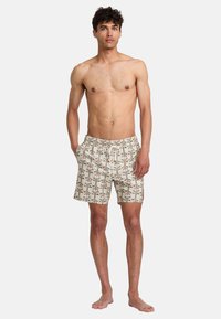 Men's swim trunks featuring a light beige fabric with colorful palm tree patterns, elastic waistband, and side pockets.