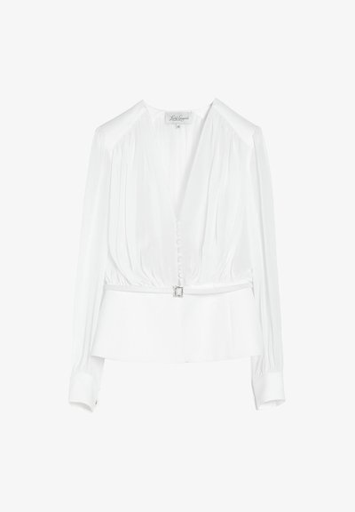 Blouse blanche à manches longues avec détails plissés, boutons recouverts sur le devant et ceinture fine avec boucle carrée à la taille.