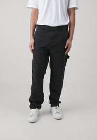 Schwarze Cargo-Hosen mit mehreren Taschen und einer lockeren Passform. Hergestellt aus robustem Material, mit einfachem Knopfverschluss und umgeschlagenen Knöcheln.