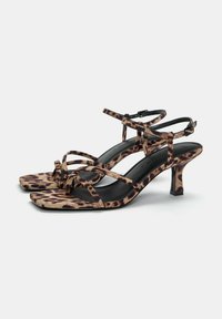 Sandales à talons hauts en imprimé léopard avec un bout carré, des fines lanières, des accents noirs et un talon élancé. Fini en daim texturé.