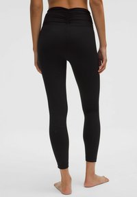 Fekete, aktív leggings, húzott derekú, szűk szabású, sima textúrájú és bokaig érő kialakítású. Nincsenek látható logók vagy kiegészítők.