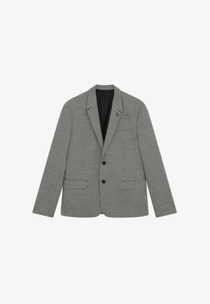 Blazer a cuadros en blanco y negro con cuello de muesca, dos bolsillos frontales y tres botones, confeccionado en una tela texturizada.