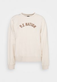 Krämfärgad sweatshirt med långa raglanärmar, rund halsringning och "P.E NATION" broderad i mörkbrunt på bröstet. Mjuk textur.