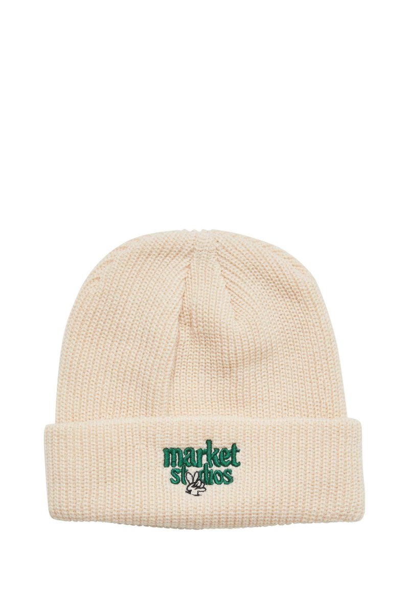 Beige pletená čepice s ohrnutým lemem, na které je zelený vyšitý text "market studios" a logo králíka. Texturovaný, měkký vzhled.