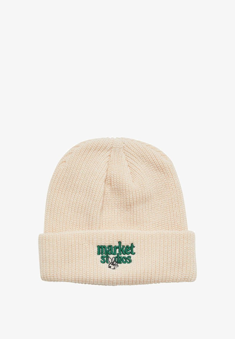 Beige pletená čepice s ohrnutým lemem, na které je zelený vyšitý text "market studios" a logo králíka. Texturovaný, měkký vzhled.