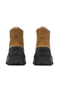 Bottes courtes en cuir marron avec un col en feutre gris, semelles en caoutchouc noir et un détail de logo proéminent à l'arrière. Surpiqûres renforcées en accent.