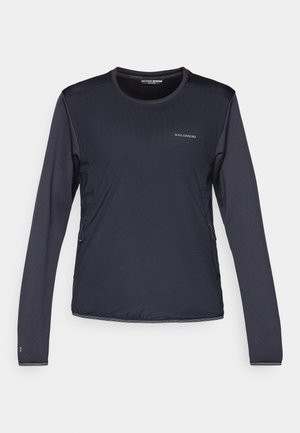 Dlouhý rukáv černého sportovního trička Salomon s kulatým výstřihem a viditelnými bočními zipovými kapsami na bílém pozadí.