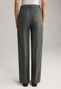 Graue maßgeschneiderte Hose aus strukturiertem Stoff, weit geschnittenes Design, Gürtelschlaufen und eine glatte Oberfläche, von hinten betrachtet.