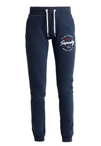 Marina blå sweatpants i mjukt tyg, med dragsko i midjan, sidofickor och vita tryckta logodetaljer på framsidan.