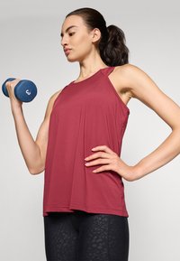 Top da allenamento senza maniche di colore bordeaux realizzato in tessuto leggero, caratterizzato da un collo rotondo e una vestibilità comoda, abbinato a leggings neri con un motivo.