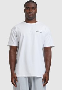 Valge puuvillane T-särk ümarate kraega. Vasakul rinnal on musta värviga trükitud tekst "unustatud näod". Mugav lõige, lühikesed varrukad.