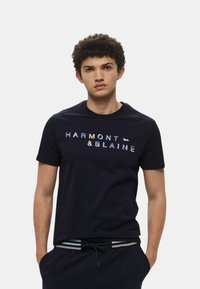 T-shirt in cotone navy a maniche corte, con la scritta "HARMONT & BLAINE" in lettere multicolori e un piccolo dettaglio del logo.
