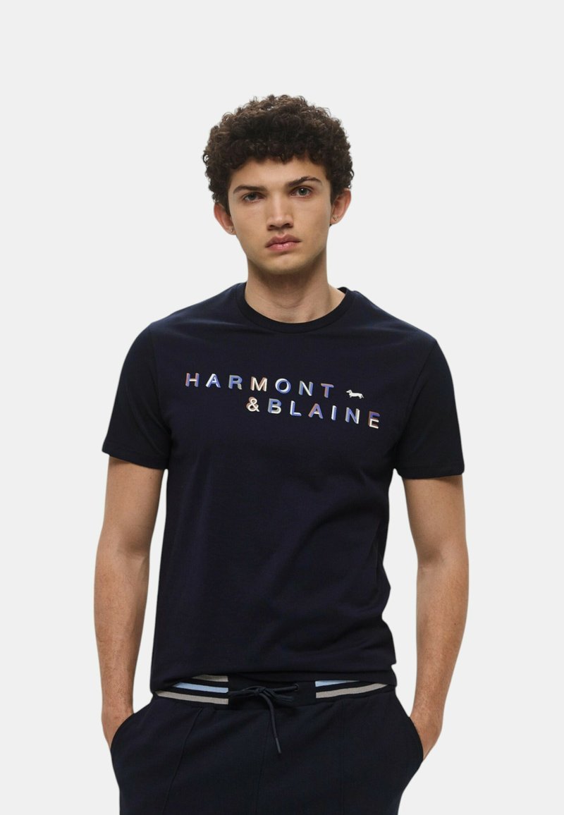 T-shirt in cotone navy a maniche corte, con la scritta "HARMONT & BLAINE" in lettere multicolori e un piccolo dettaglio del logo.