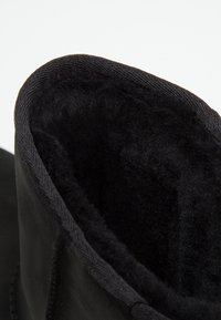 Gros plan d'une bottine d'hiver noire montrant une doublure intérieure douce et pelucheuse conçue pour la chaleur et le confort.