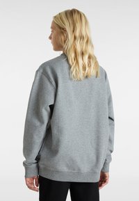 Grå sweatshirt i mjukt material, med avslappnad passform, rund halsringning och långa ärmar. Diskret sömdetaljering längs axlarna.