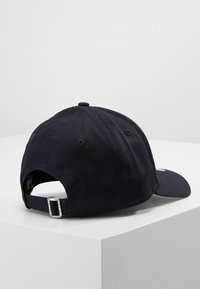Sötét navy kék baseball sapka, pamutból készült, ívelt karimával, állítható pánttal a hátulján és szellőzőlyukakkal a tetején.
