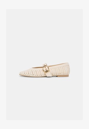 Beigen värinen matala kenkä, jossa on terävä kärki, rei'itetty päällinen ja koristeellinen kultainen solkiside sivulla.