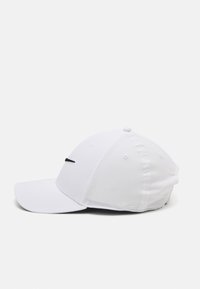 Valge põhjatriibuga baseballi müts, mis on valmistatud kangast ja millel on kõver nokk, õmmeldud paneelid ning ees väike must logo.