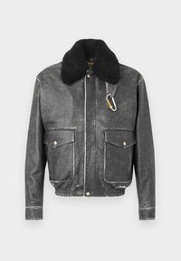 Veste en cuir noir avec un col en shearling noir ; se distingue par deux poches frontales, des coutures blanches et un accent en carabine en argent.