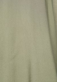 Jasnozielony materiał o miękkiej, gładkiej fakturze, prezentujący subtelny połysk i jednolity wzór tkaniny na całej powierzchni.