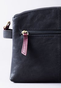 Black leather pouch with a top zipper, featuring a maroon leather pull tab and contrasting stitching. Smooth texture with a structured shape.