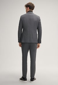 Grauer Zweiteiler mit strukturiertem Muster, schlankem Schnitt, Jacke mit Einzelventil, kombiniert mit schwarzen Sneakers. Rückansicht dargestellt.