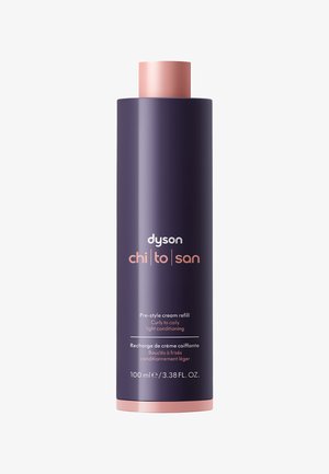 Bottiglia cilindrica viola scuro con tappo rosa. Il testo indica che si tratta di una ricarica da 100 ml di crema pre-styling per capelli ricci a molto ricci.